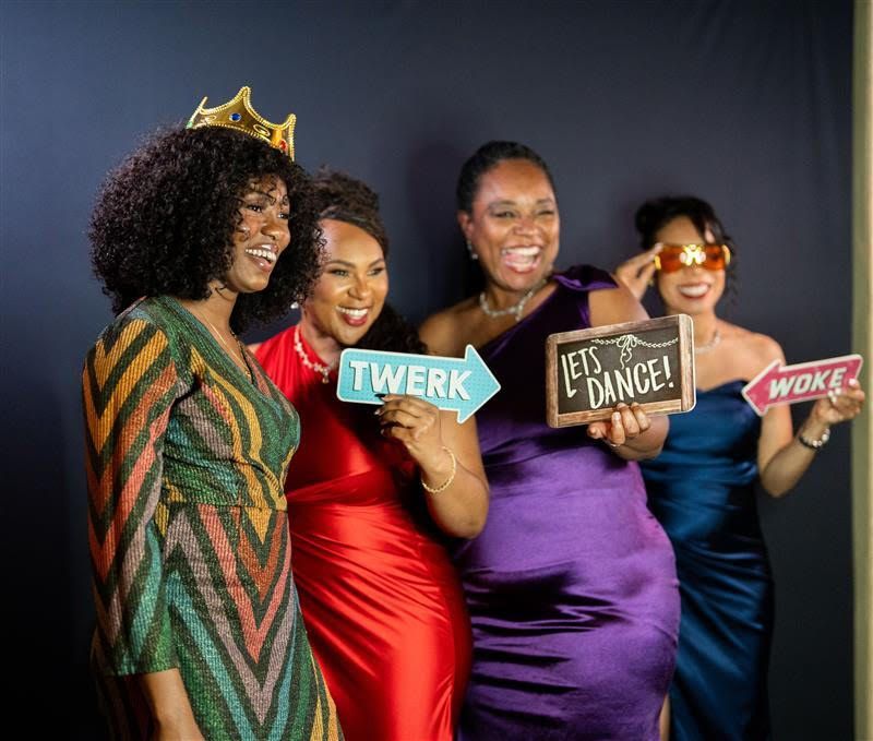 A group of women are taking a selfie in a photo booth.