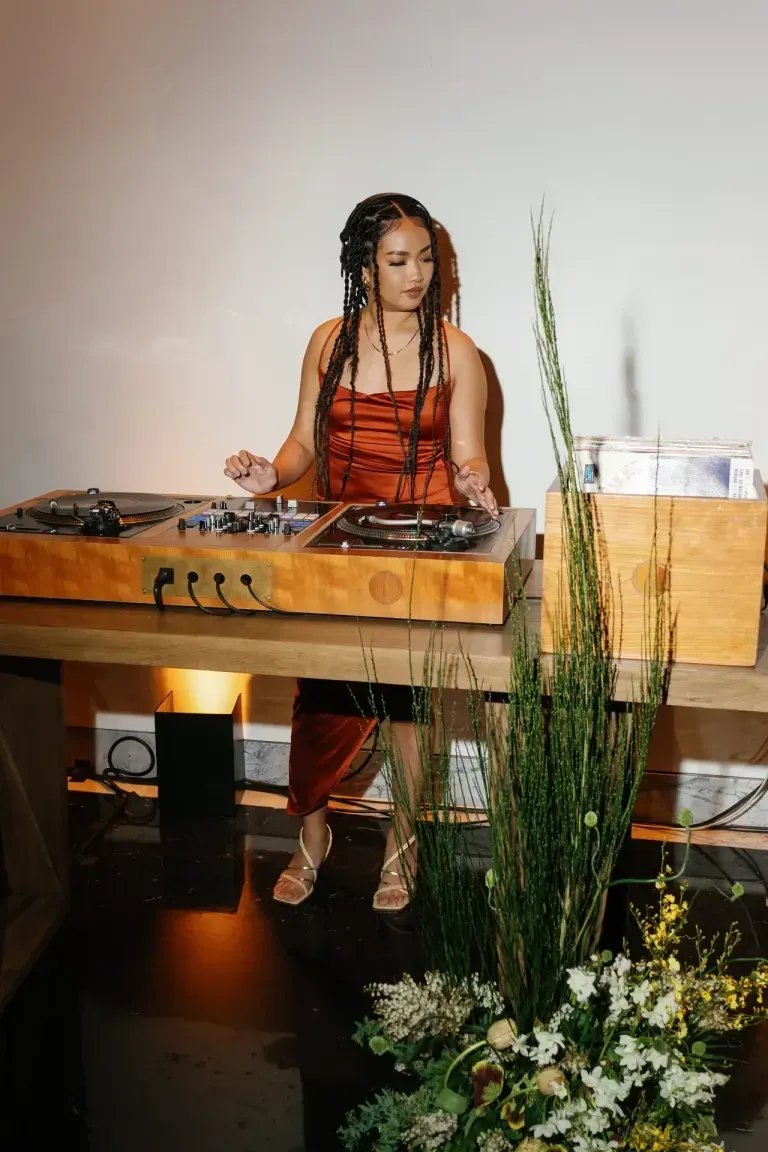 A woman is sitting at a table playing music on a turntable.