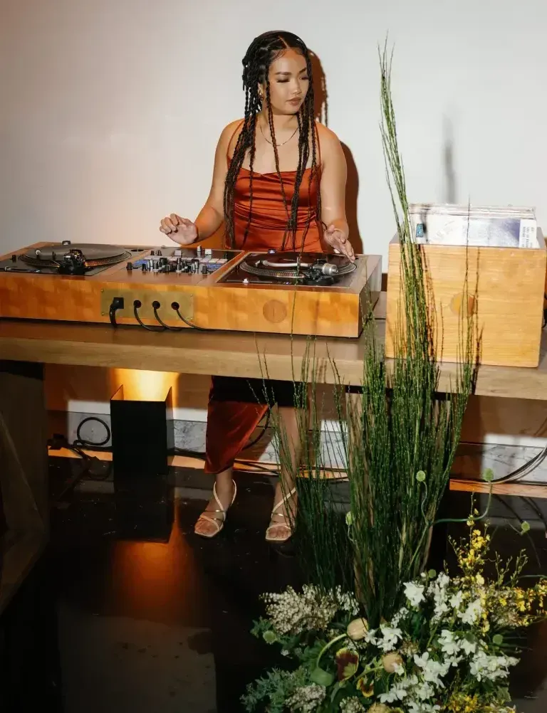 A woman is sitting at a table playing music on a turntable.