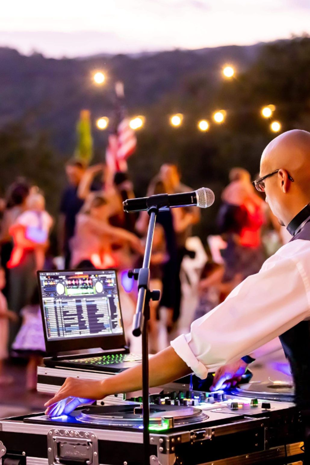 A man is playing music on a laptop at a party.