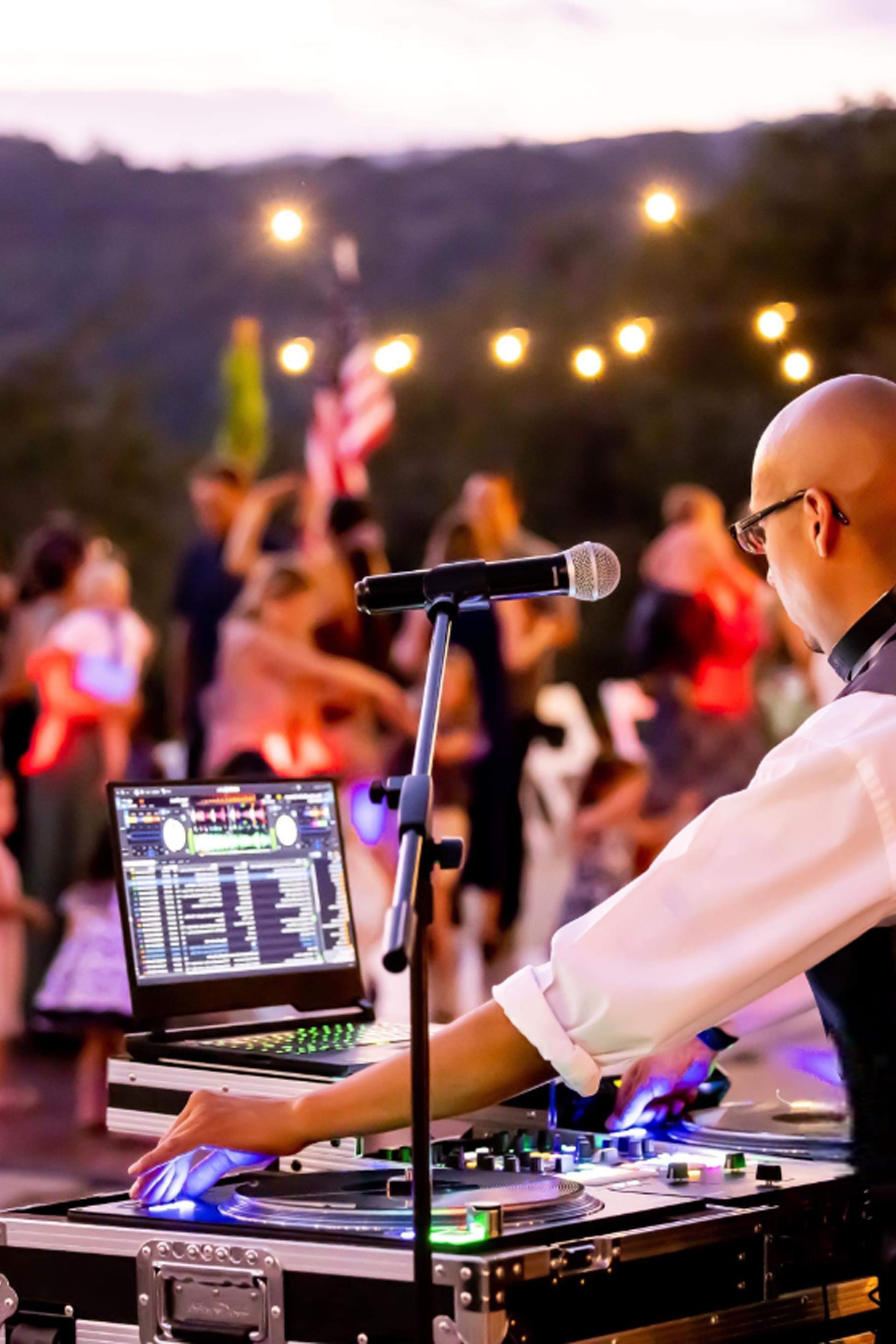 A man is playing music on a laptop at a party.