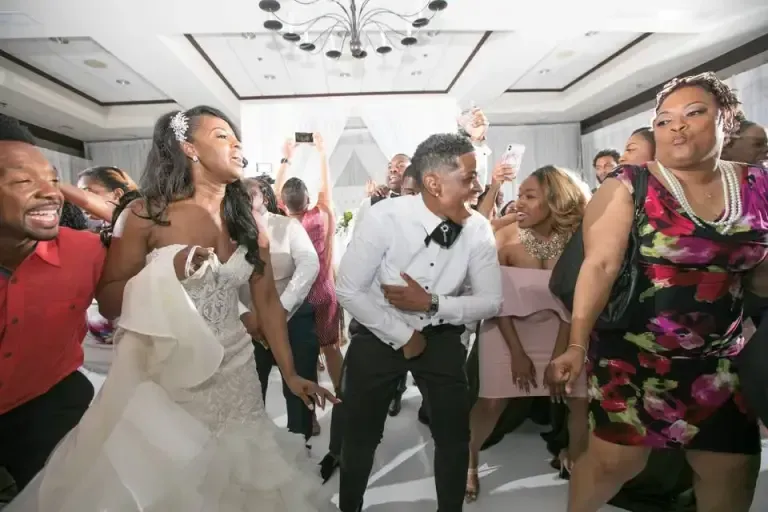 A bride and groom are dancing with their wedding party at their wedding reception.