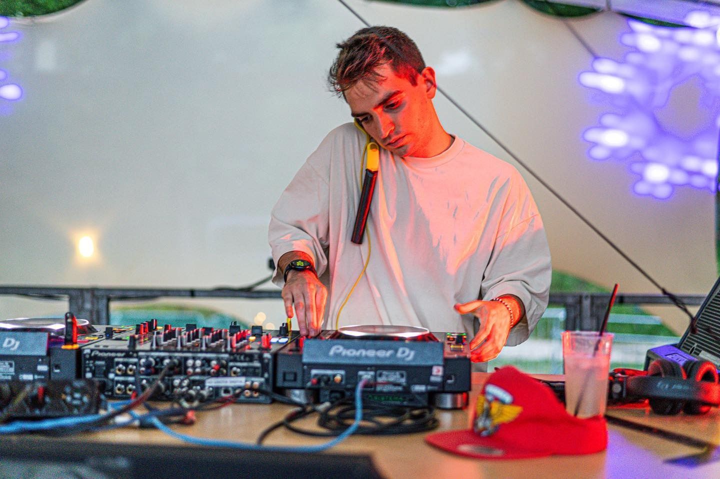DJ a un evento musicale che indossa un abito chiaro e mixa i brani con un'espressione concentrata.