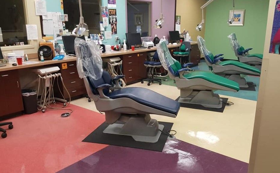 Dental office with blue and green chairs, colorful floors, and dental equipment.