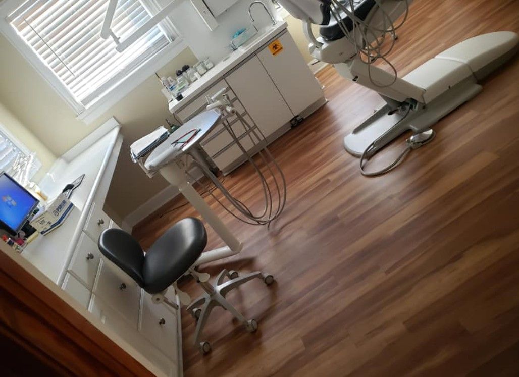 A dental office with chair, equipment, cabinetry, and a window.