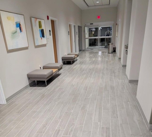 Hallway with benches, artwork, and exit door, light gray tile flooring.