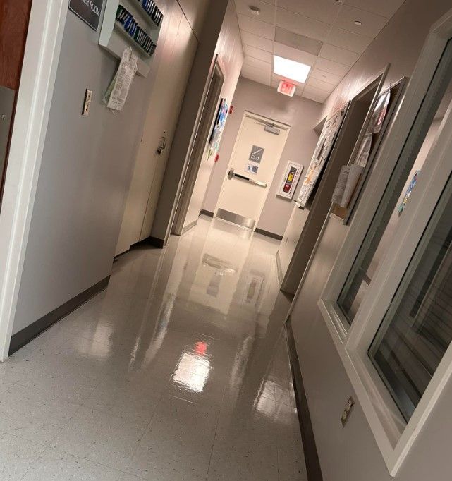 Hallway with glossy floor, doors, windows, and emergency equipment.