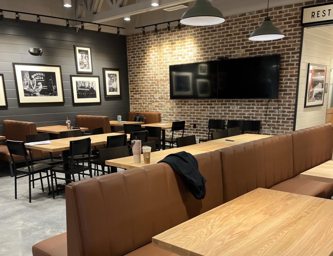 Restaurant interior with tables, booths, brick walls, and framed photos.