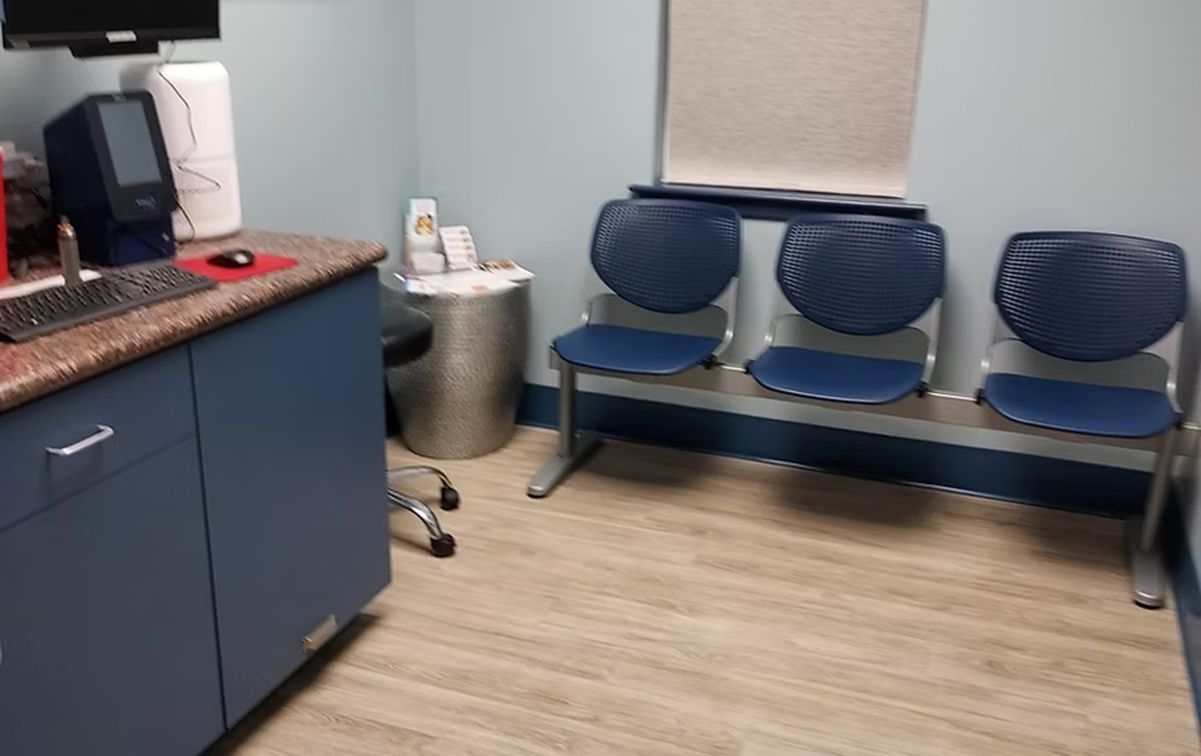 A waiting room with blue chairs and a computer