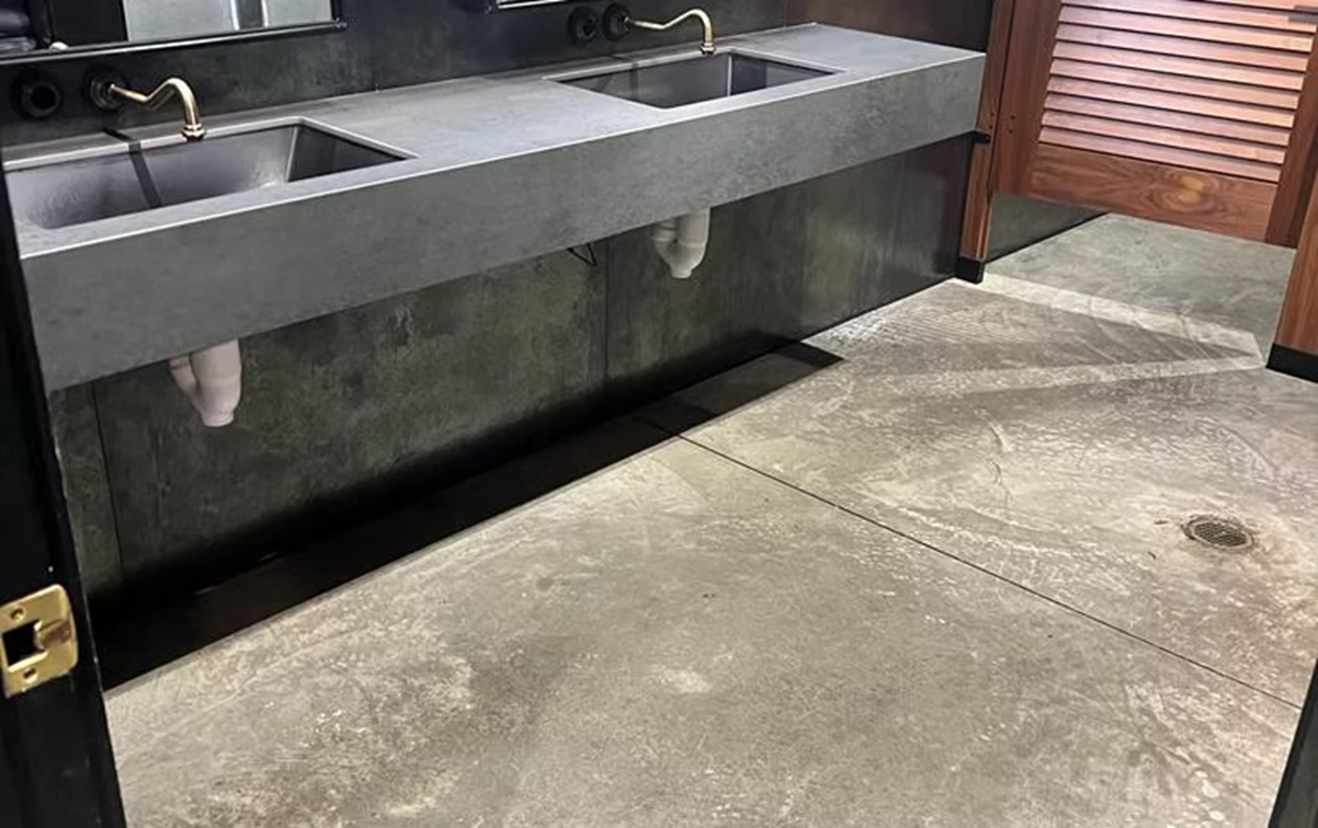 A bathroom with two sinks and a concrete floor.