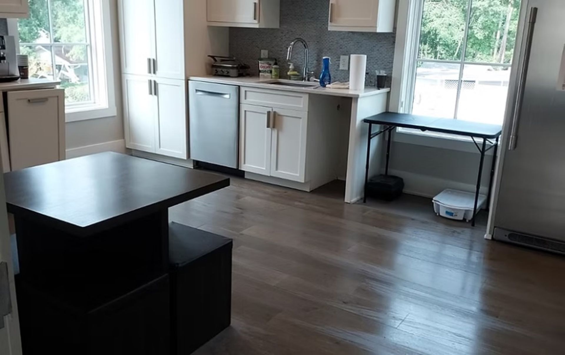 A kitchen with a table , refrigerator , sink and dishwasher.