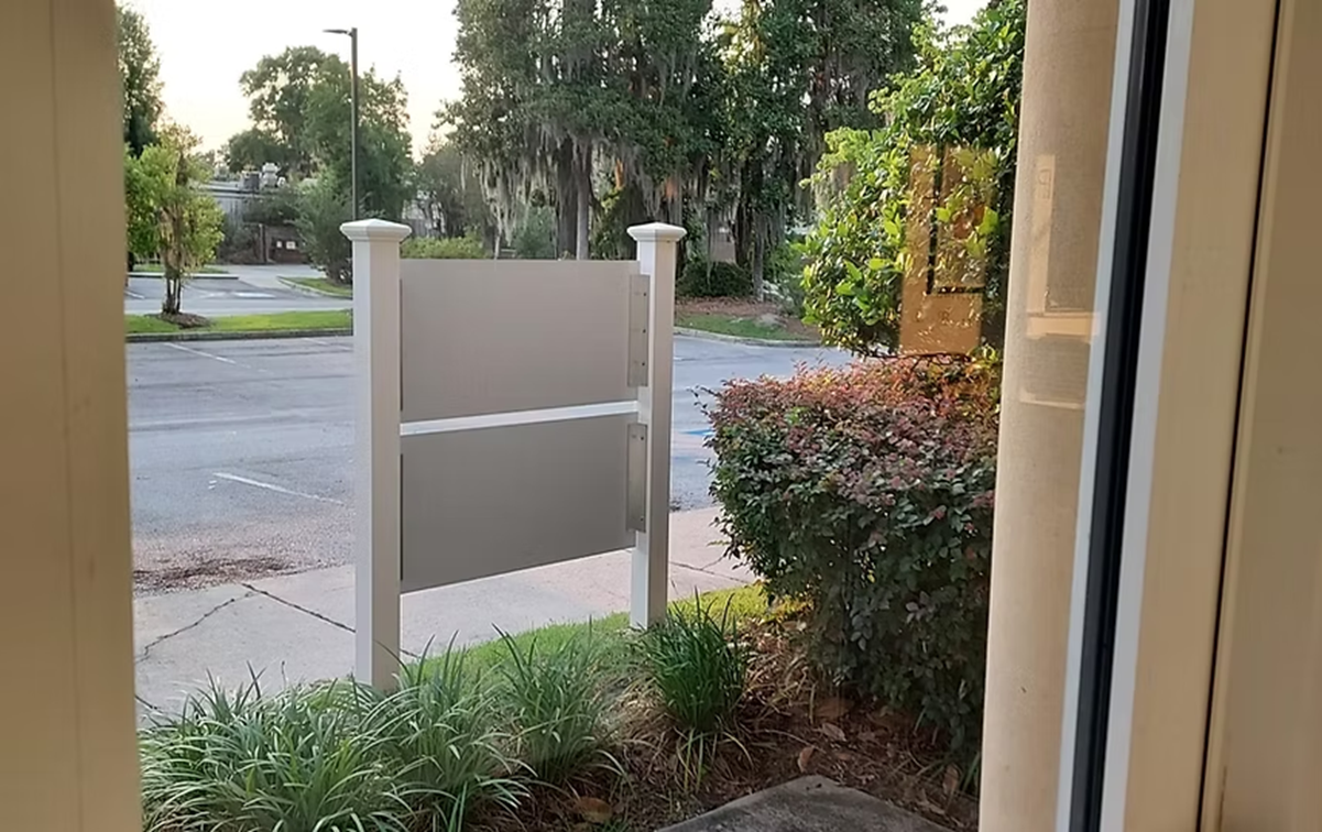 A view of a street from a window with a sign in the foreground.