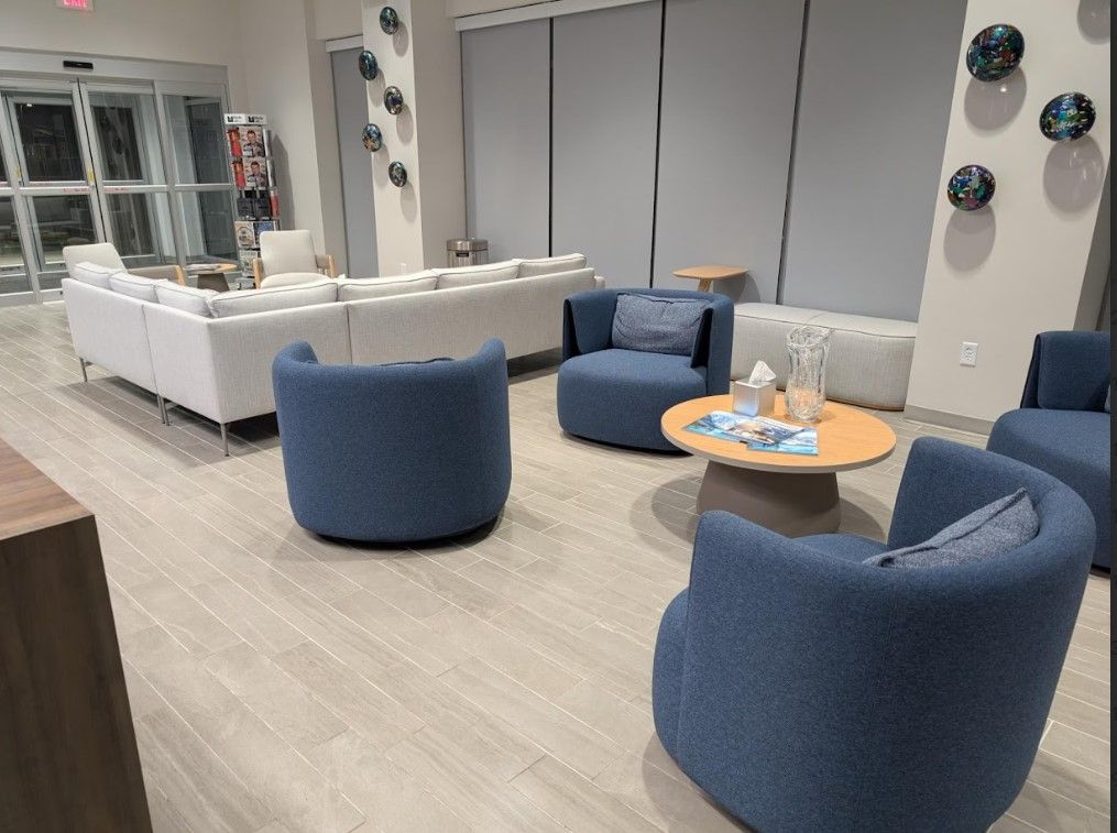 Lounge area with blue chairs, a light sectional sofa, and a round coffee table.