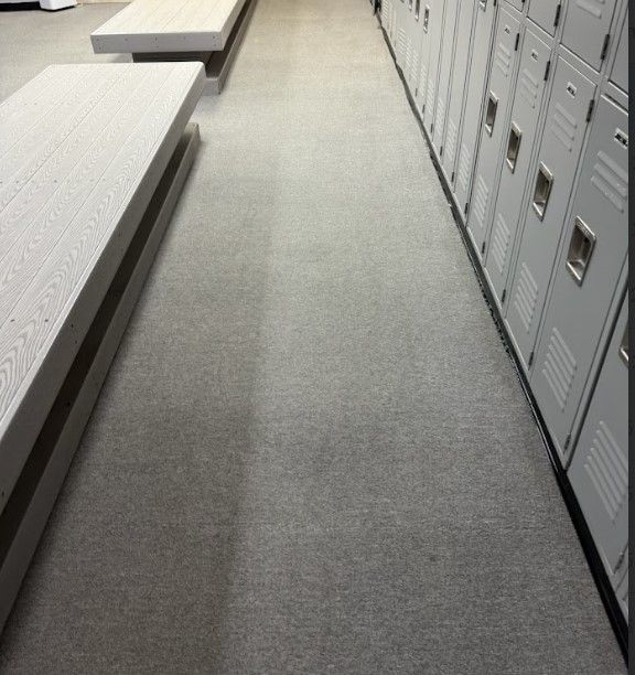 Long hallway with lockers on one side and benches on the other; gray carpet.