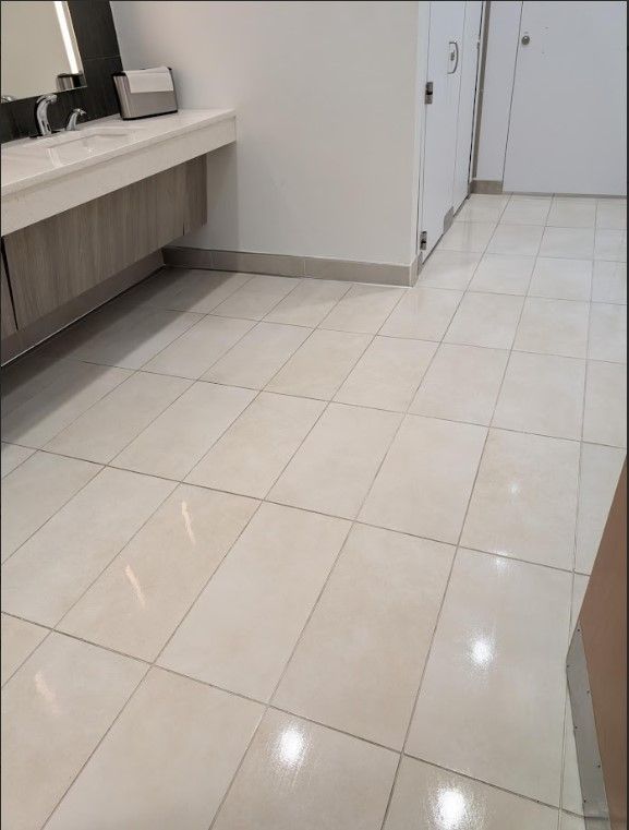 Bathroom with white tiled floor, sinks, and stalls.