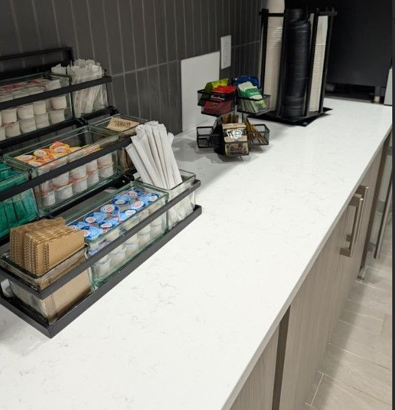 Coffee station: white countertop with condiment containers, coffee cups, and coffee dispensers.