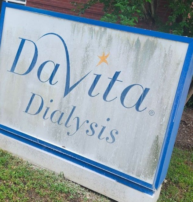 DaVita Dialysis sign, weathered with blue and gray lettering and a blue border.