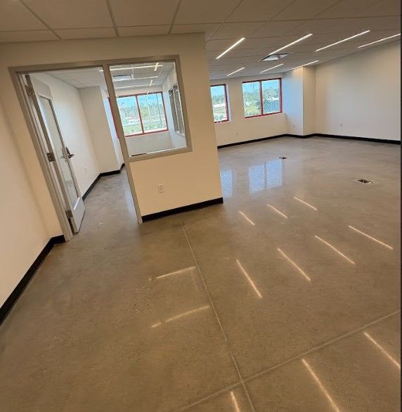 Empty office with polished concrete floor, white walls, and windows.