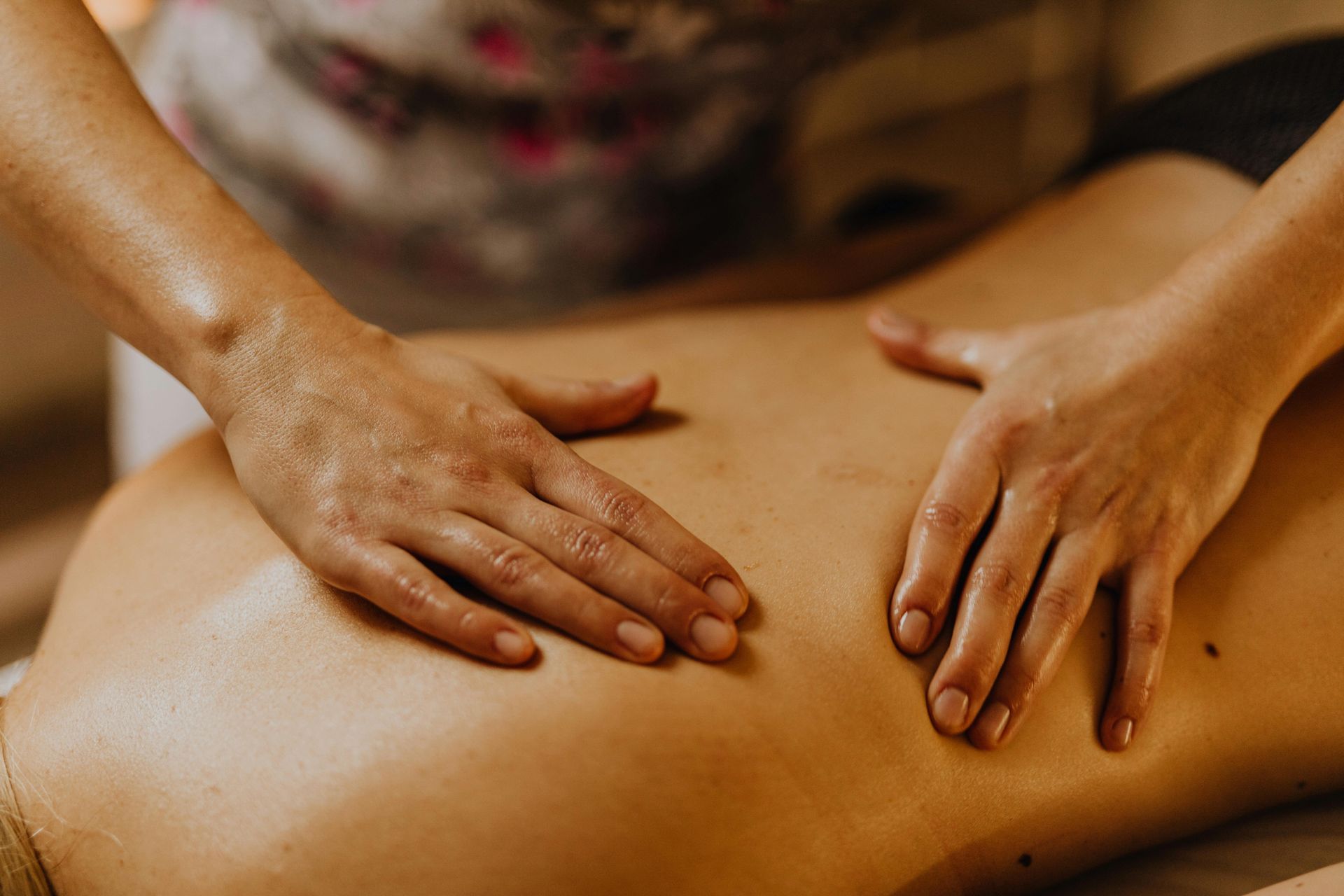 A close-up view of a massage therapist performing a back massage on a person lying down on a massage table.
