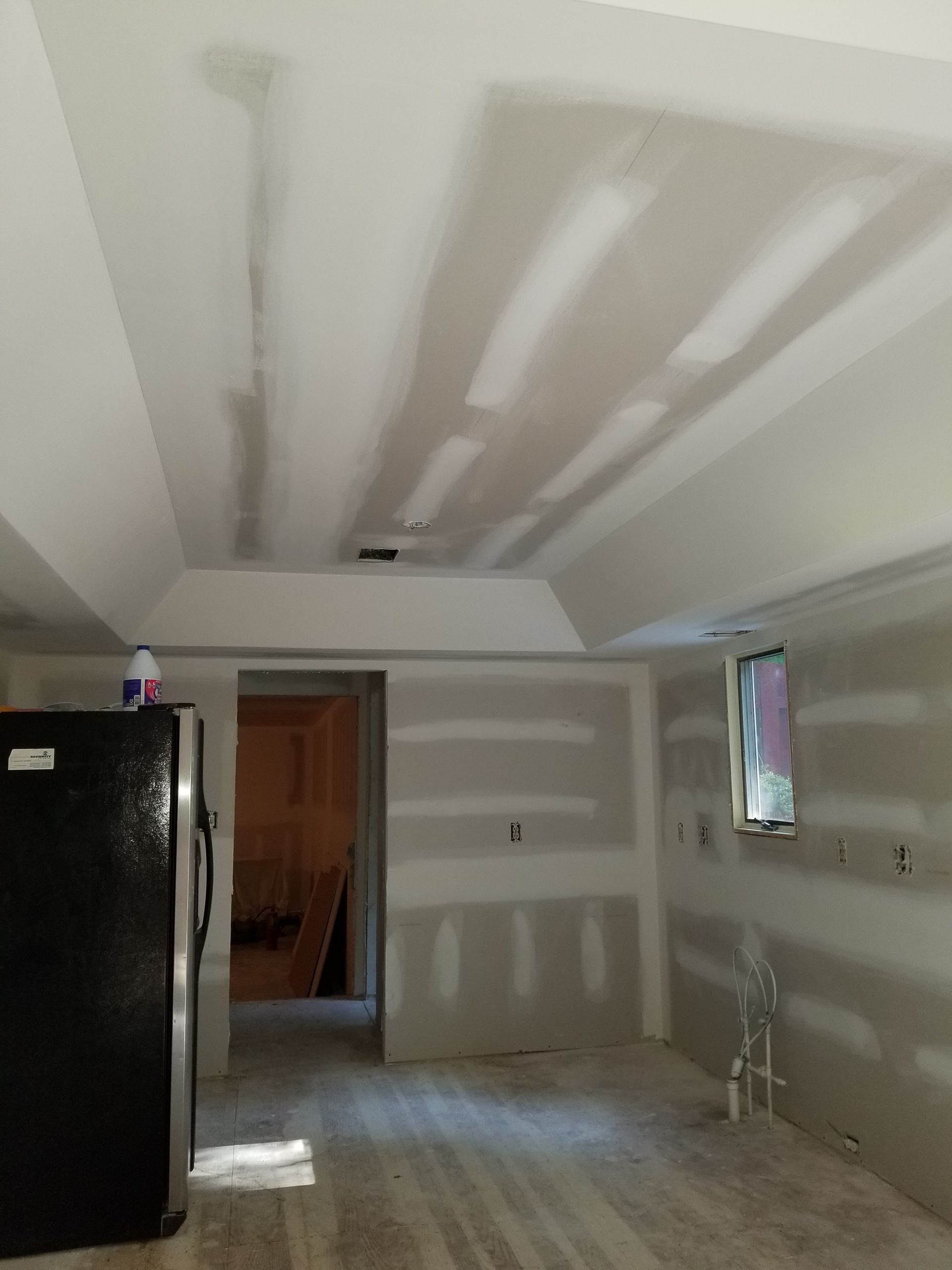 There is a black refrigerator in the middle of the room.