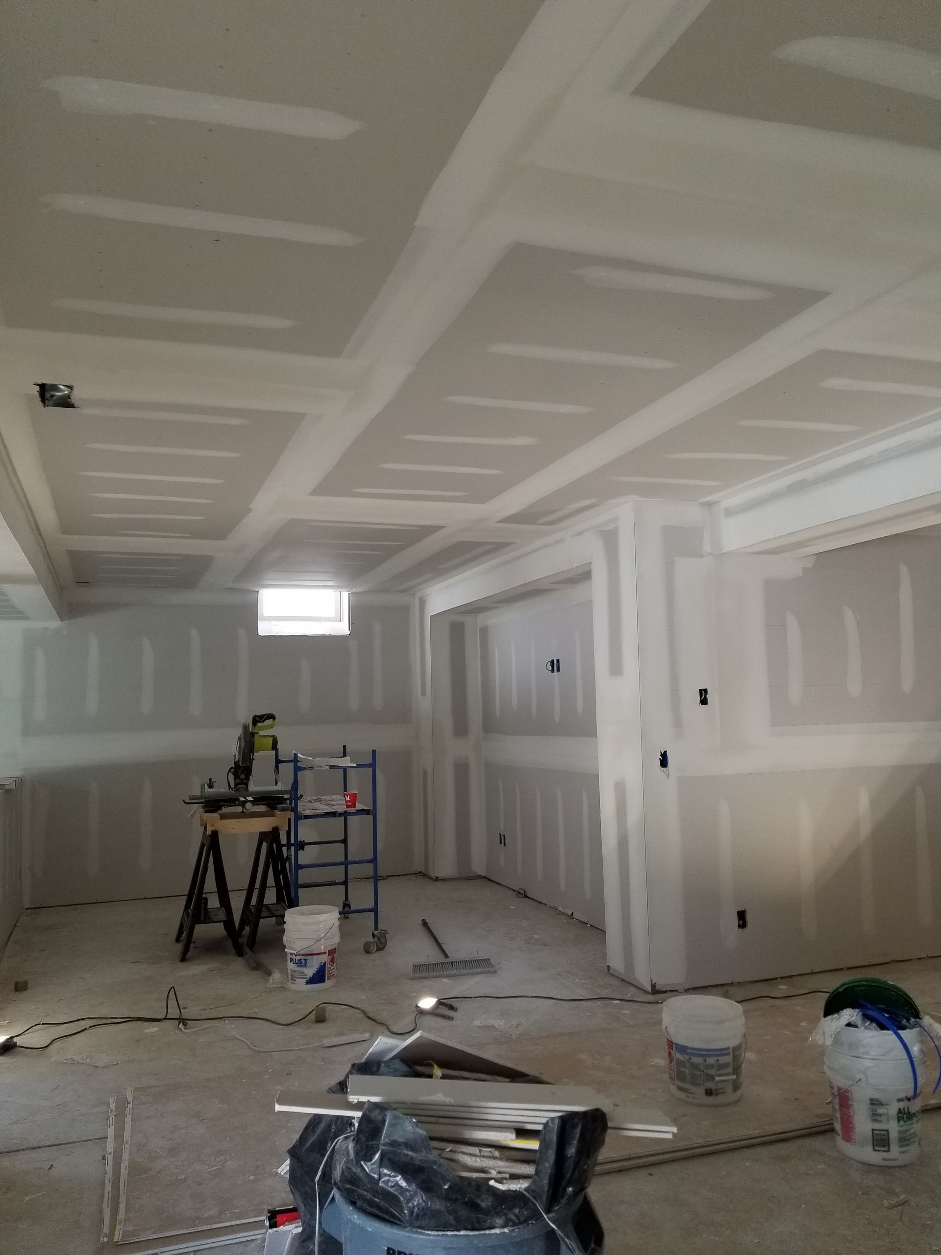 A room with a lot of drywall and a ladder in it