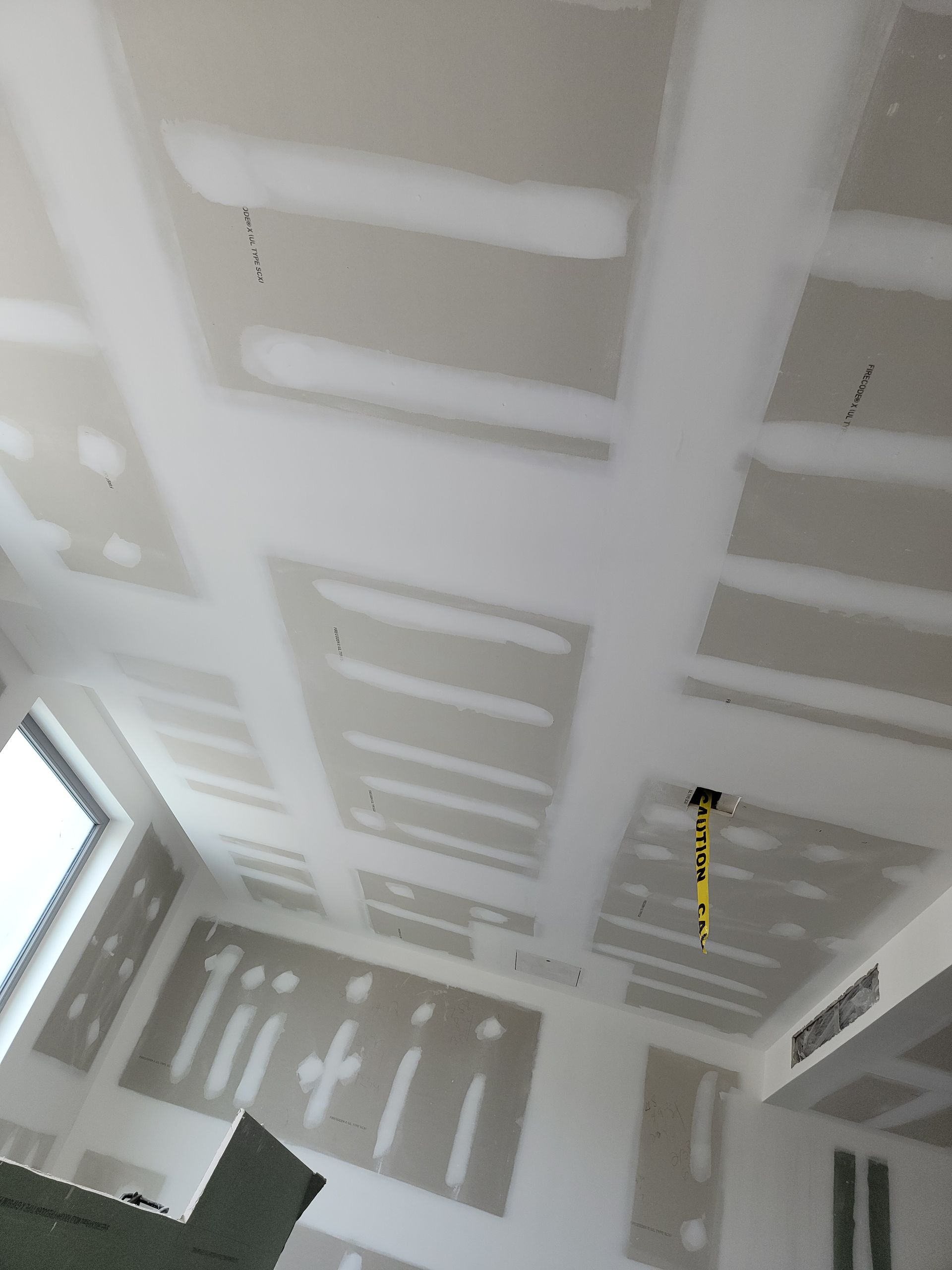 A room with a ceiling that has a yellow tape measure hanging from it