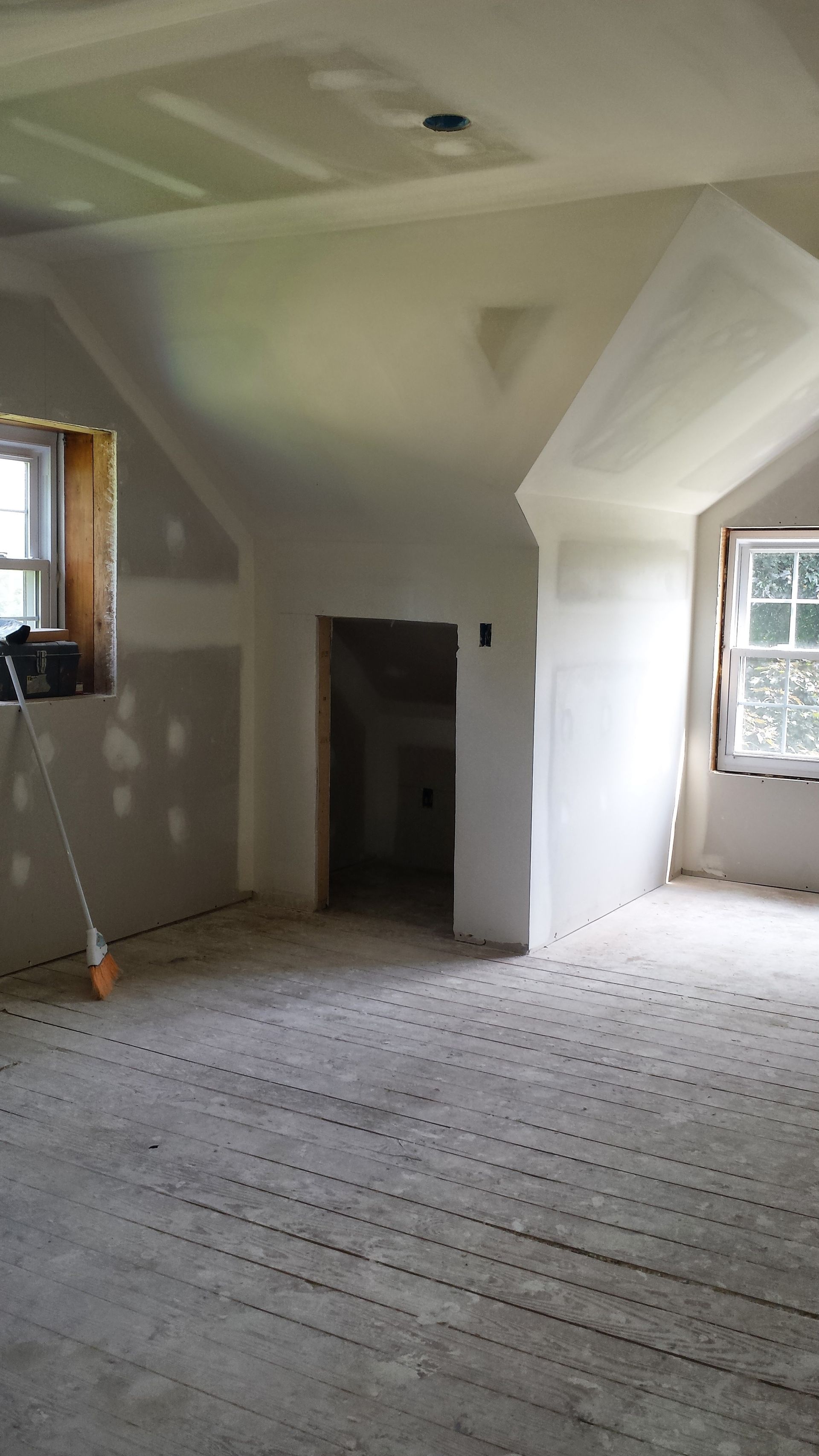An empty room with a broom in it and a window.