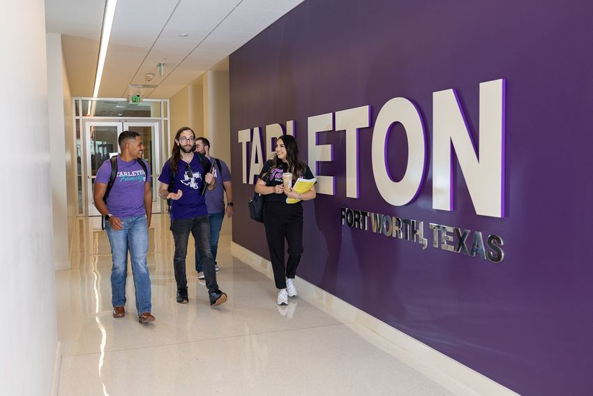 4 students walking down hallway on campus