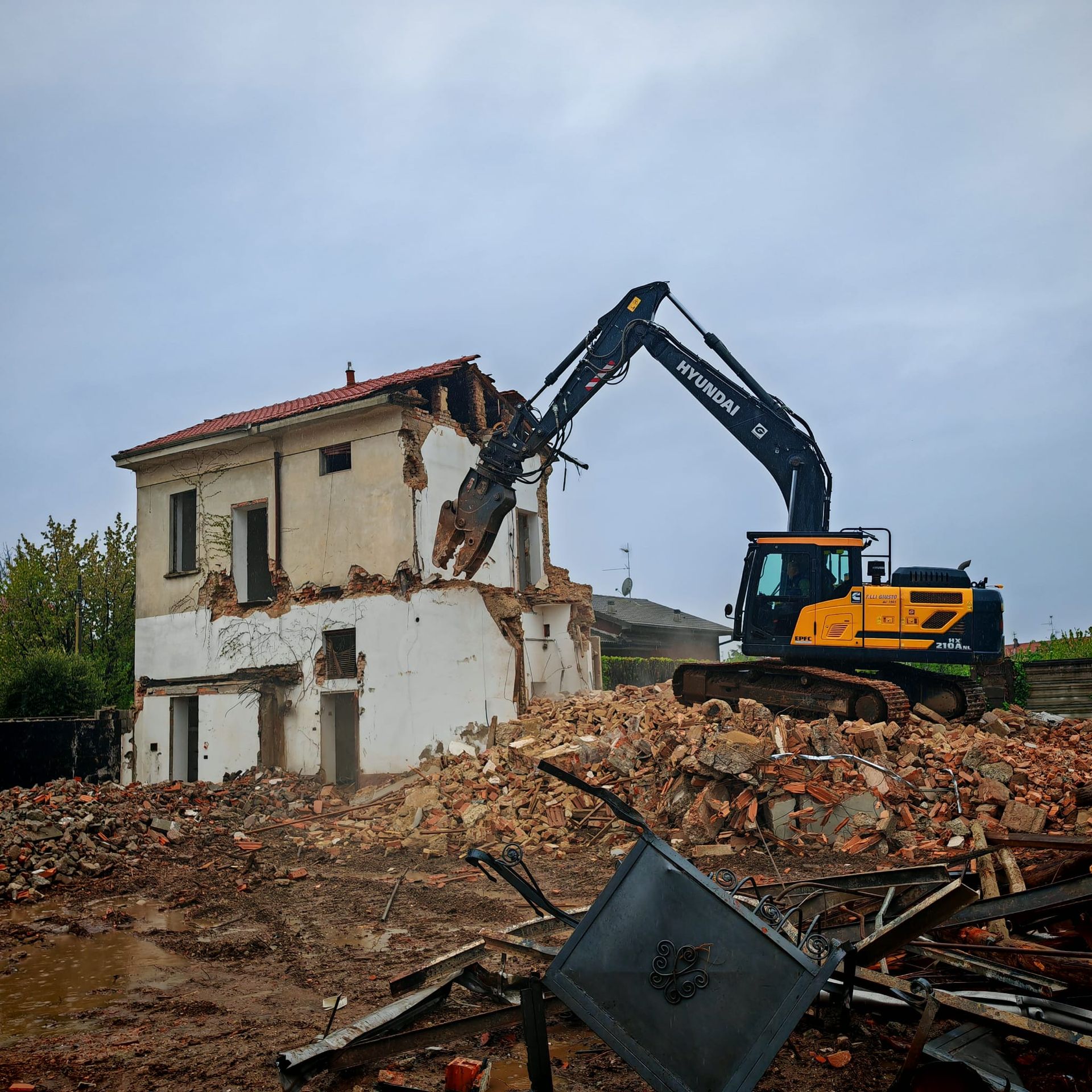 Un camion con cassone ribaltabile viene caricato con delle rocce davanti a un edificio.