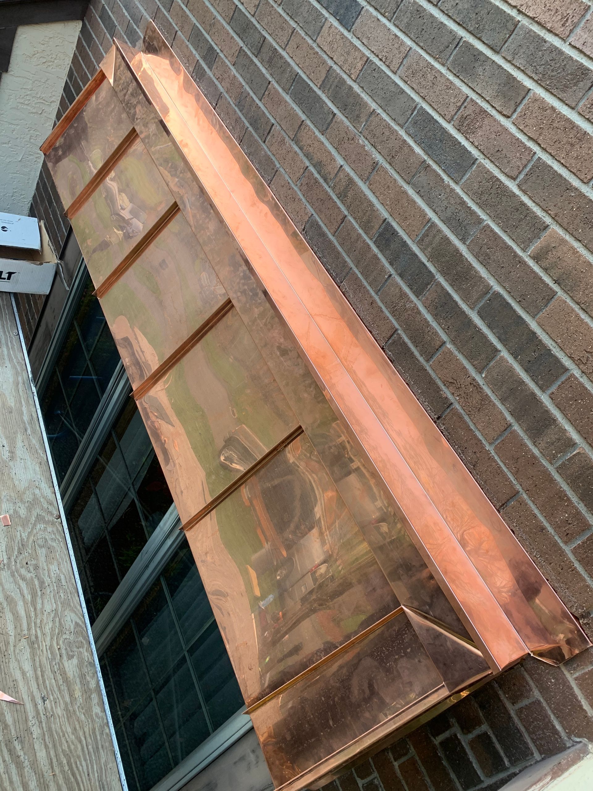 A row of brick buildings with slate roofs and chimneys against a blue sky.