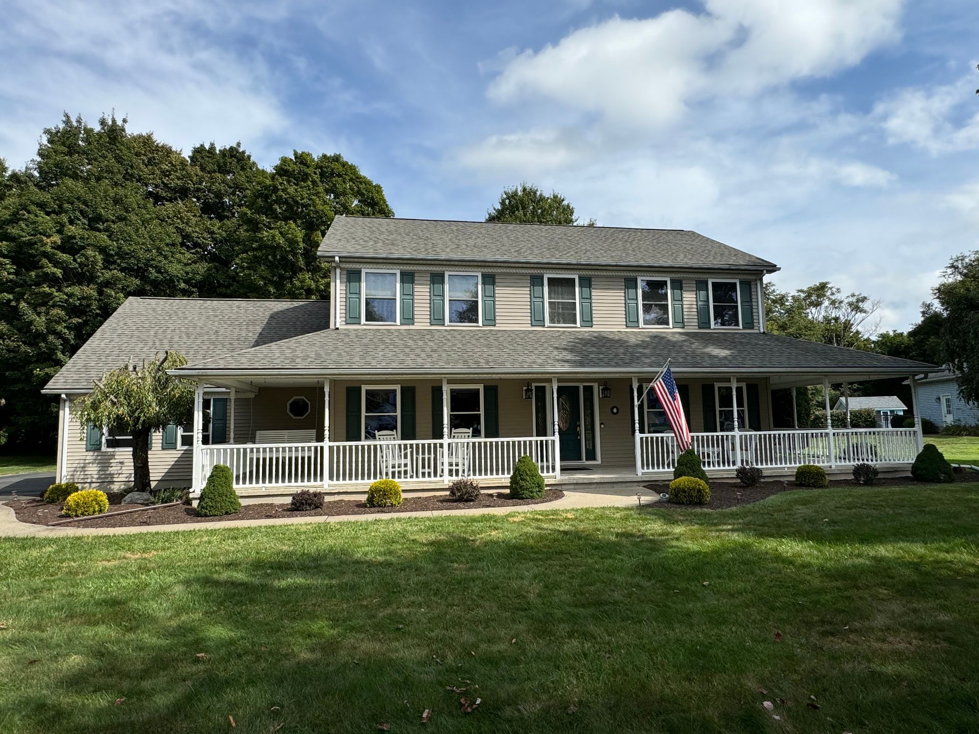 A large house with a large porch and a flag on it.