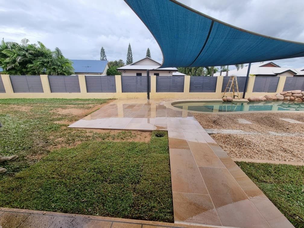 A Swimming Pool With a Blue Umbrella Over It — Lynams Landscapes Pty Ltd in Kirwan, QLD