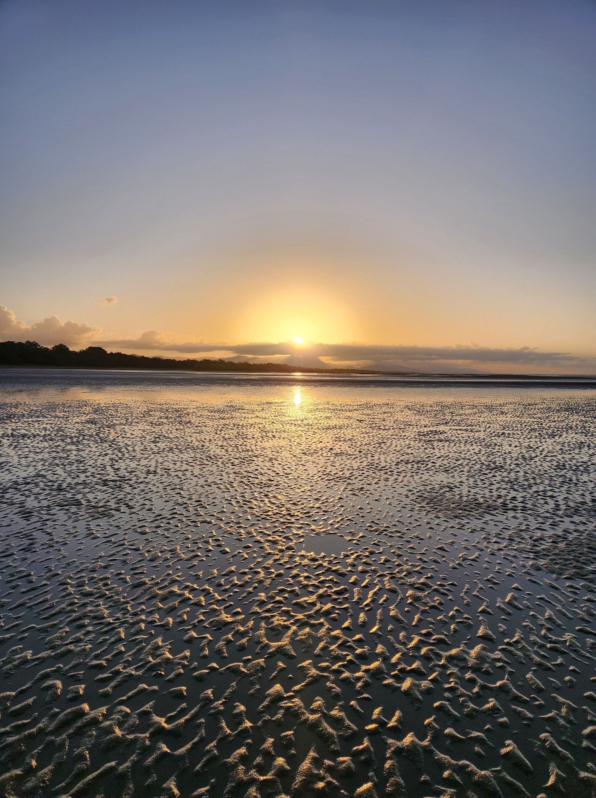 The sun is setting over a body of water — Lynams Landscapes Pty Ltd in Bushland Beach, QLD