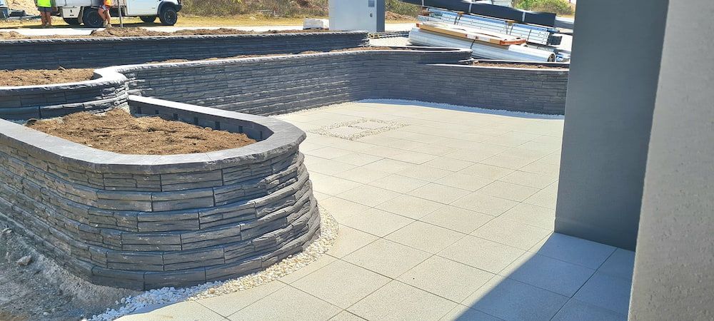 A Brick Wall is Being Built Next to a Concrete Walkway — Lynams Landscapes Pty Ltd in Jensen, QLD