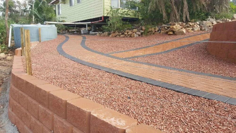 A Brick Wall Surrounds a Gravel Path Leading to a House — Lynams Landscapes Pty Ltd in Jensen, QLD