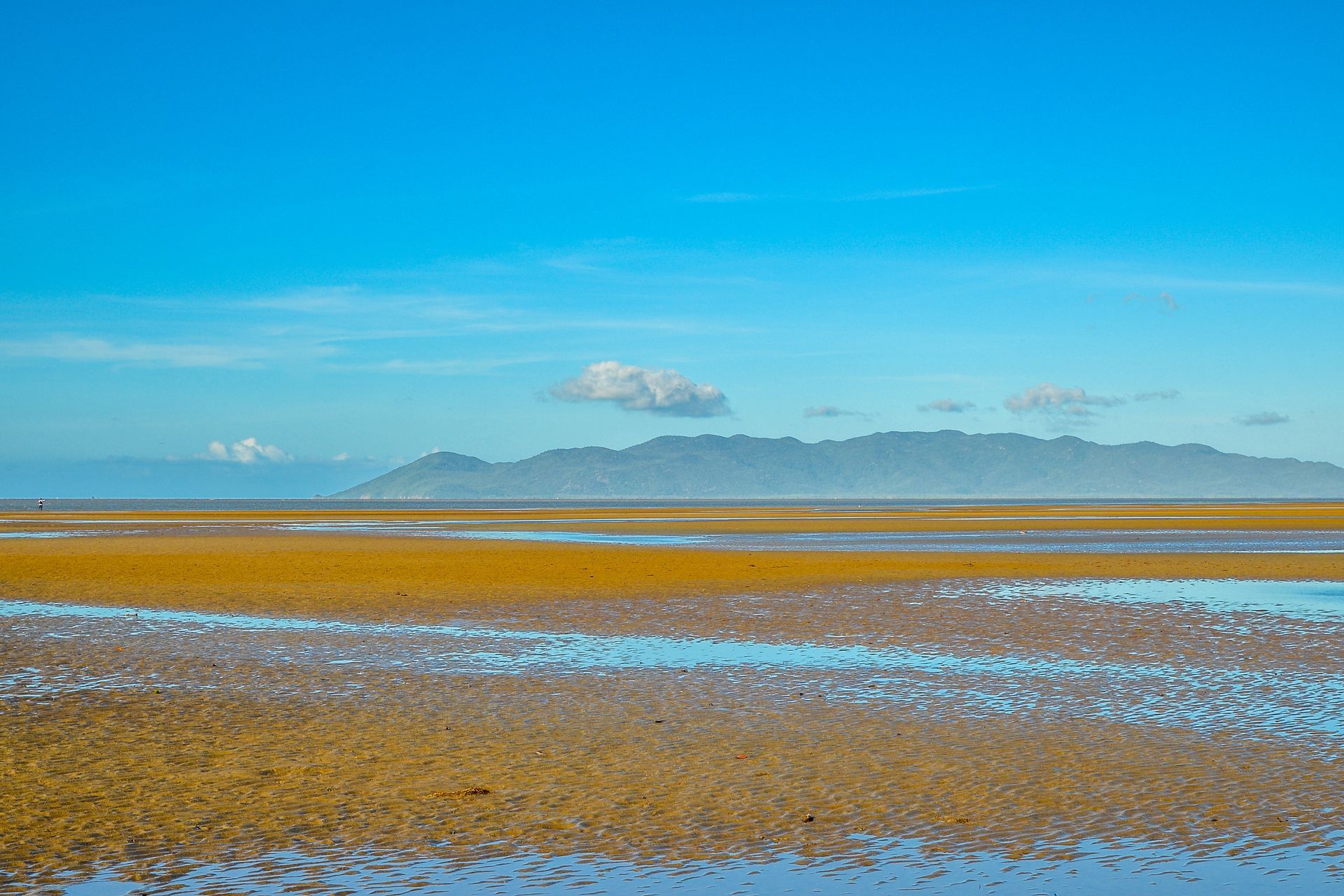 A large body of water with mountains in the background and a blue sky — Lynams Landscapes Pty Ltd in Bushland Beach, QLD