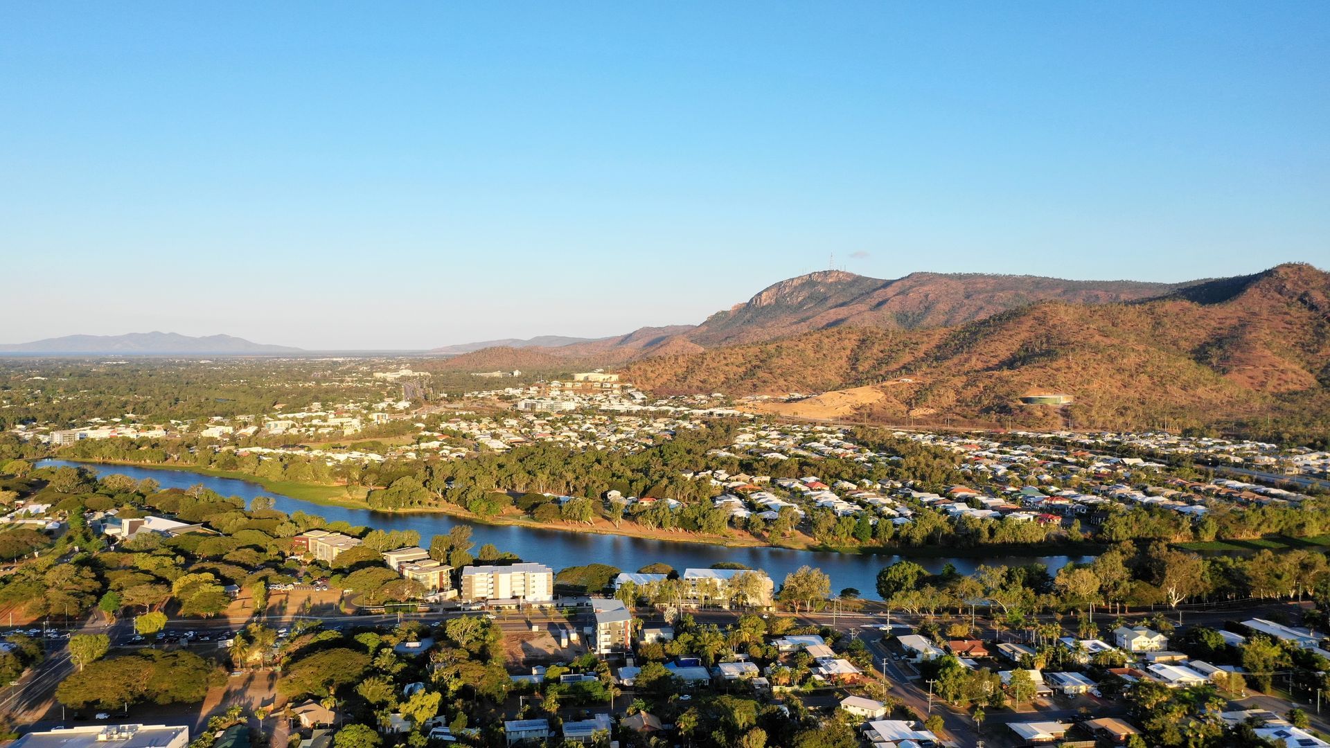 An aerial view of a city with a lake and mountains in the background — Lynams Landscapes Pty Ltd in Douglas, QLD