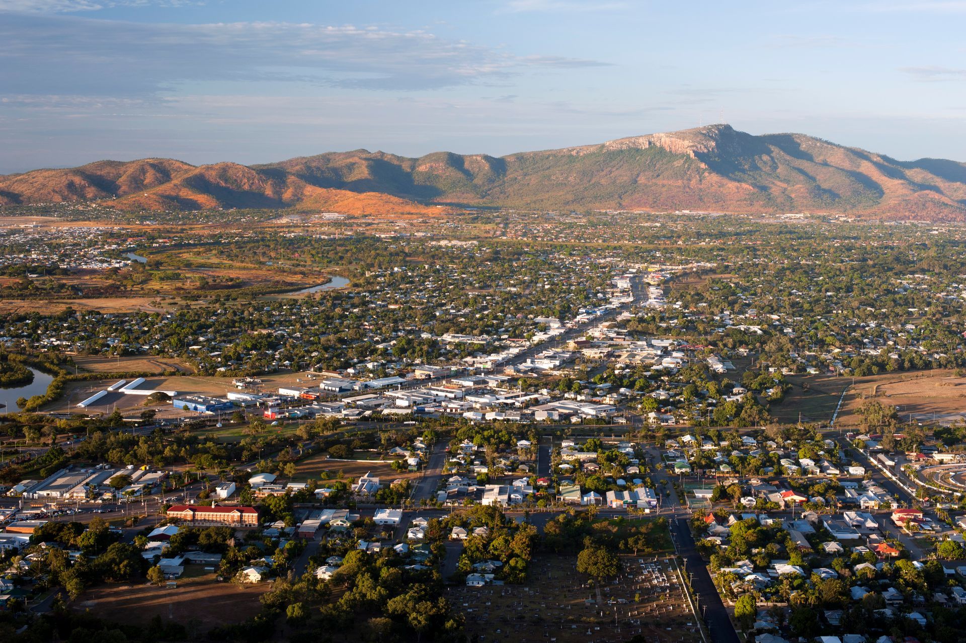 An aerial view of a city with mountains in the background — Lynams Landscapes Pty Ltd in Cosgrove, QLD