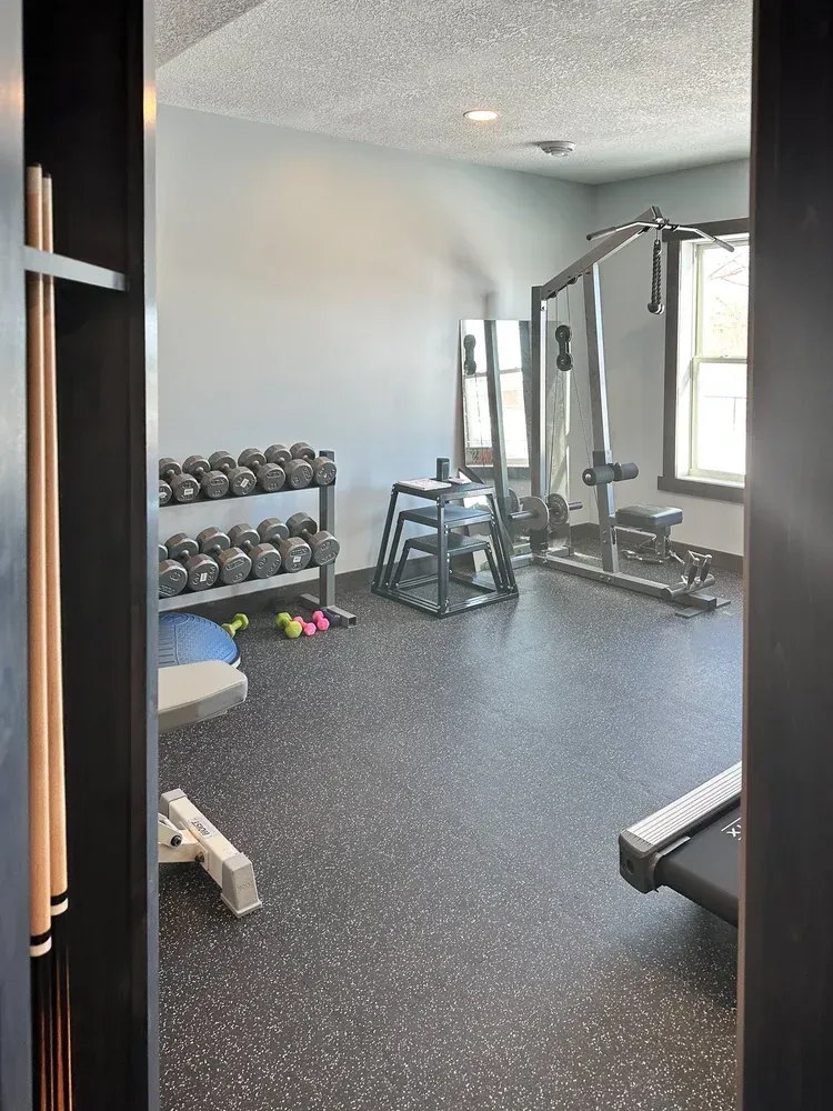 Gym room with weights, exercise equipment, and a treadmill.