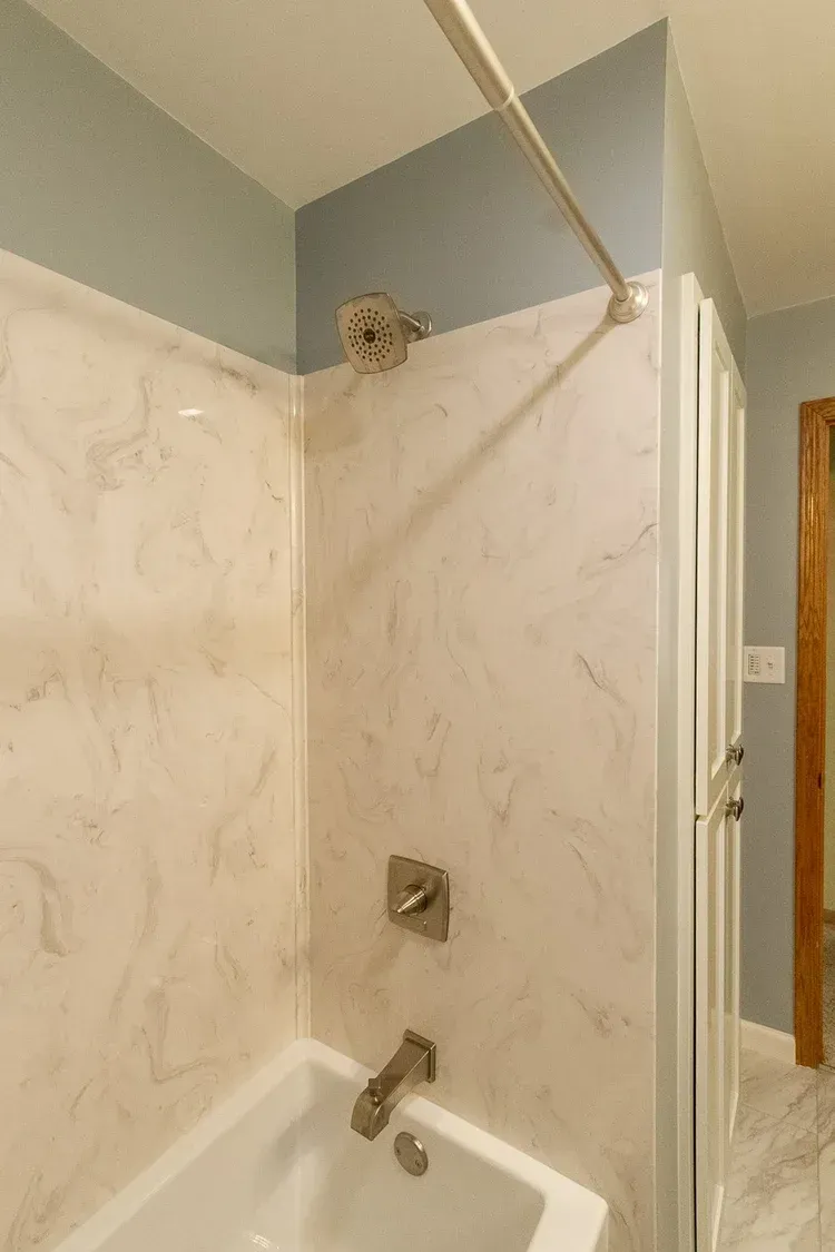 Shower with marble-like walls, silver fixtures, and blue wall paint.
