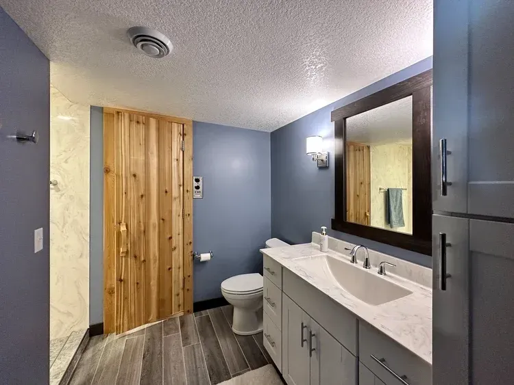 Bathroom with gray vanity, wooden door, blue walls, and a gray floor.