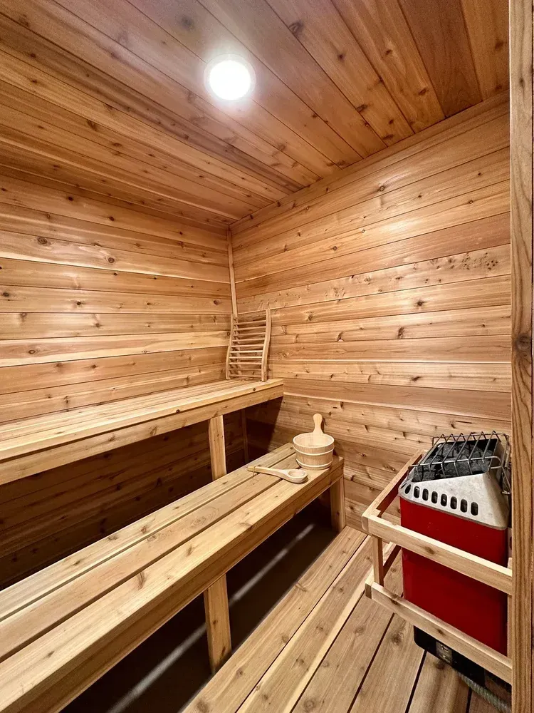 Wooden sauna with benches, heater, and accessories.
