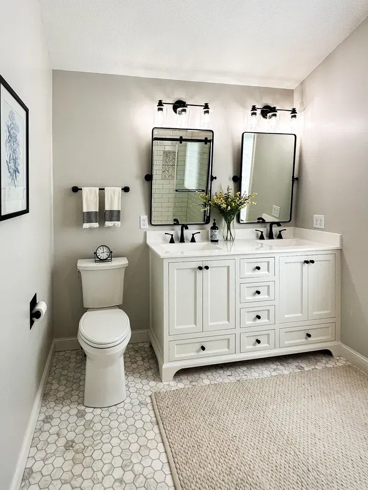 Bathroom with a white vanity, mirrors, and a patterned tile floor.