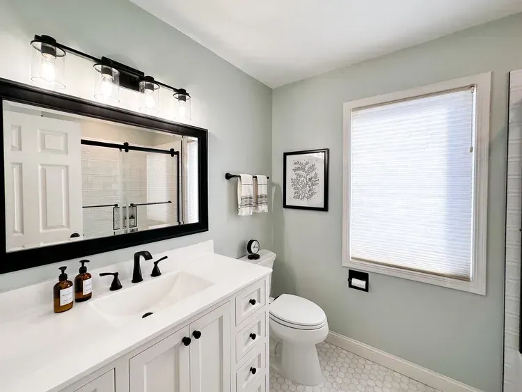 Bathroom with white vanity, black accents, and light green walls.
