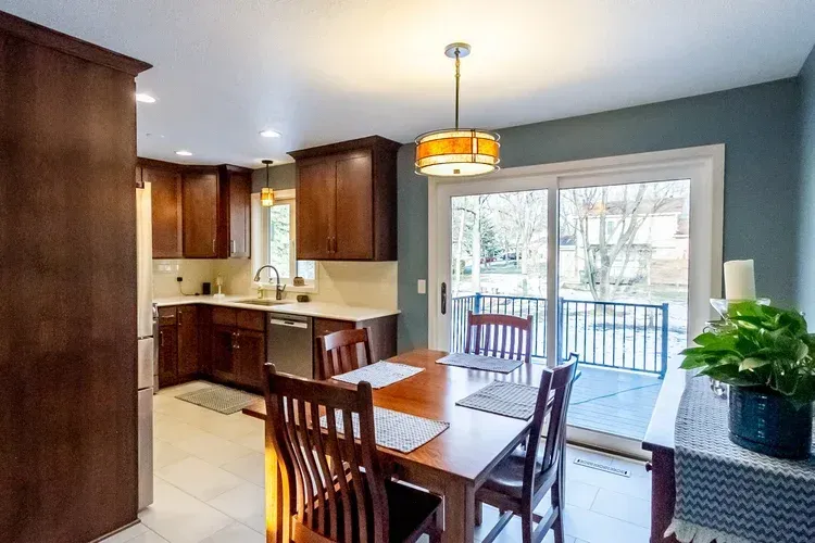 Kitchen with wooden cabinets, dining table set for four, and sliding glass doors to a deck.