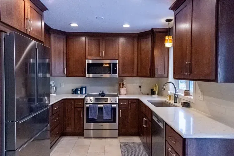 U-shaped kitchen with stainless steel appliances, brown cabinets, and white countertops.