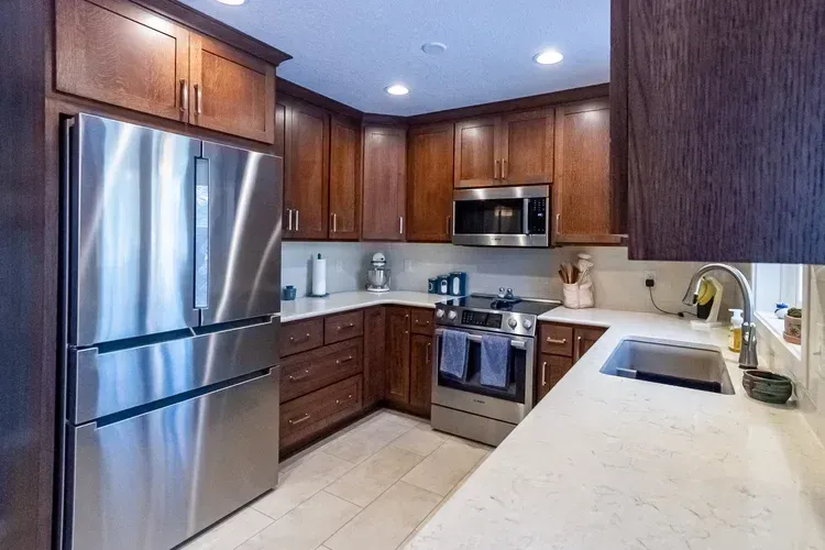 Kitchen with dark wood cabinets, stainless steel appliances, and white countertops.