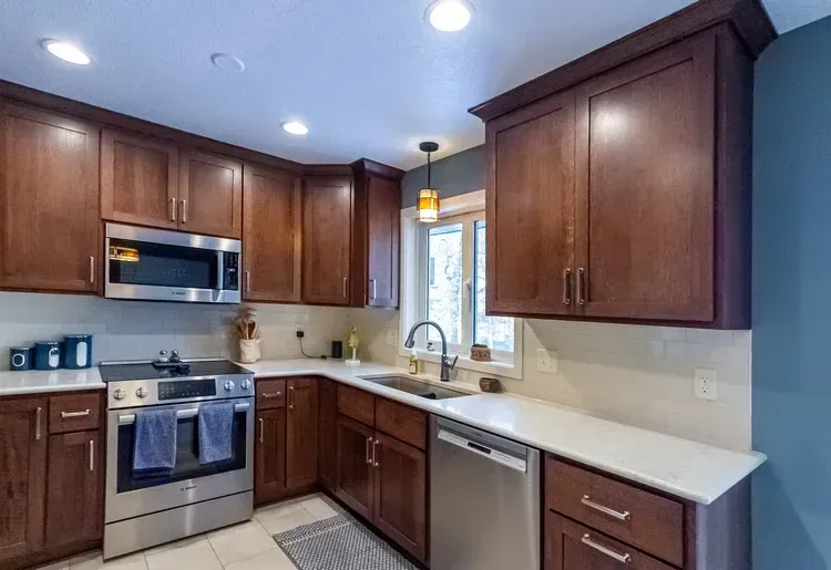 Kitchen with brown cabinets, white countertops, stainless steel appliances, and a blue wall.