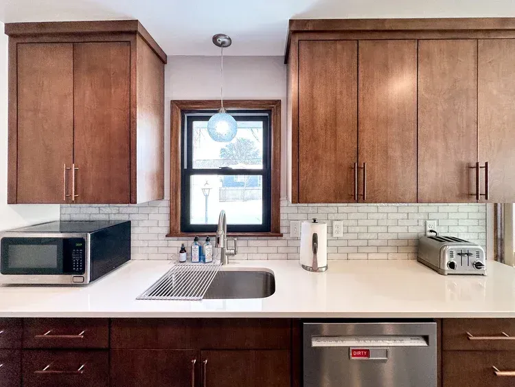 Kitchen with wood cabinets, white countertops, stainless steel appliances, and subway tile backsplash.