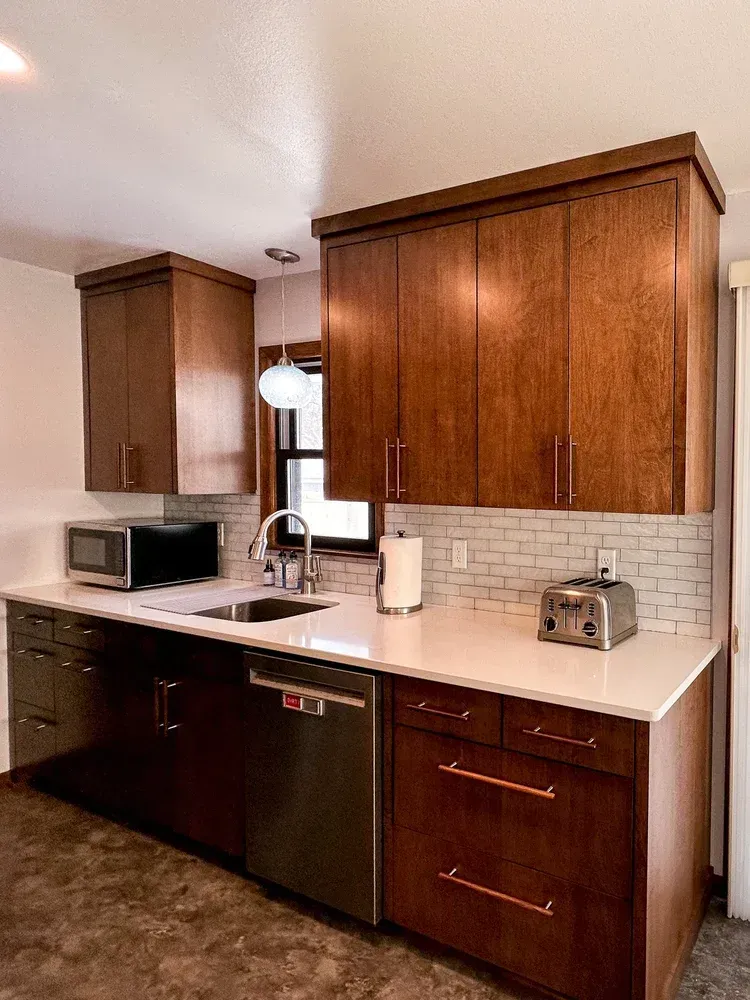 Modern kitchen with brown cabinets, white countertops, and stainless steel appliances.